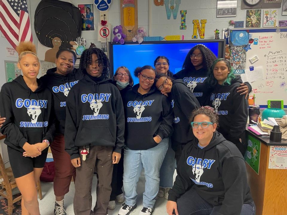 Coach Emily Gwin, bottom right, poses for a photo with the Godby High School swim team in her classroom.