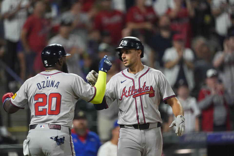 Atlanta Braves' Marcell Ozuna, left, congratulates Matt Olson, right, who crosses home plate after hitting a two-run home run off Colorado Rockies relief pitcher Angel Chivilli in the seventh inning of a baseball game Saturday, Aug. 10, 2024, in Denver. (AP Photo/David Zalubowski)