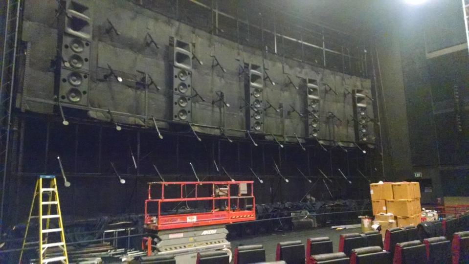 Speakers on the back of the screen, scaffolding, and a ladder