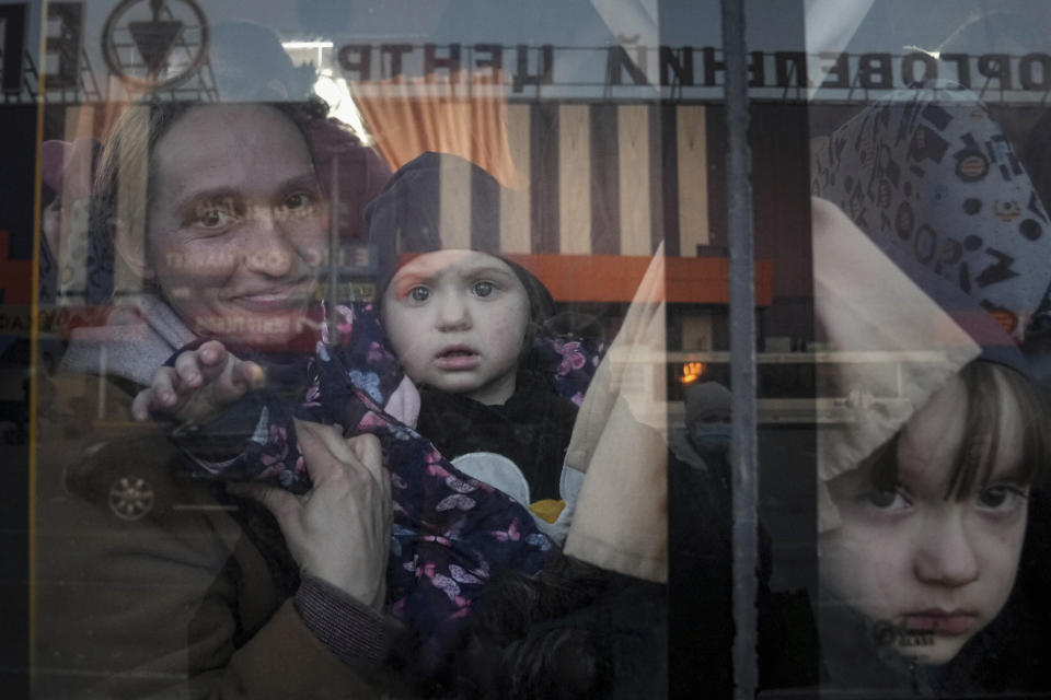 Displaced Ukrainians look out from a bus at a refugee center.