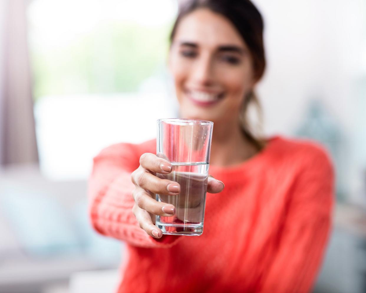 young woman showing drinking glass with water