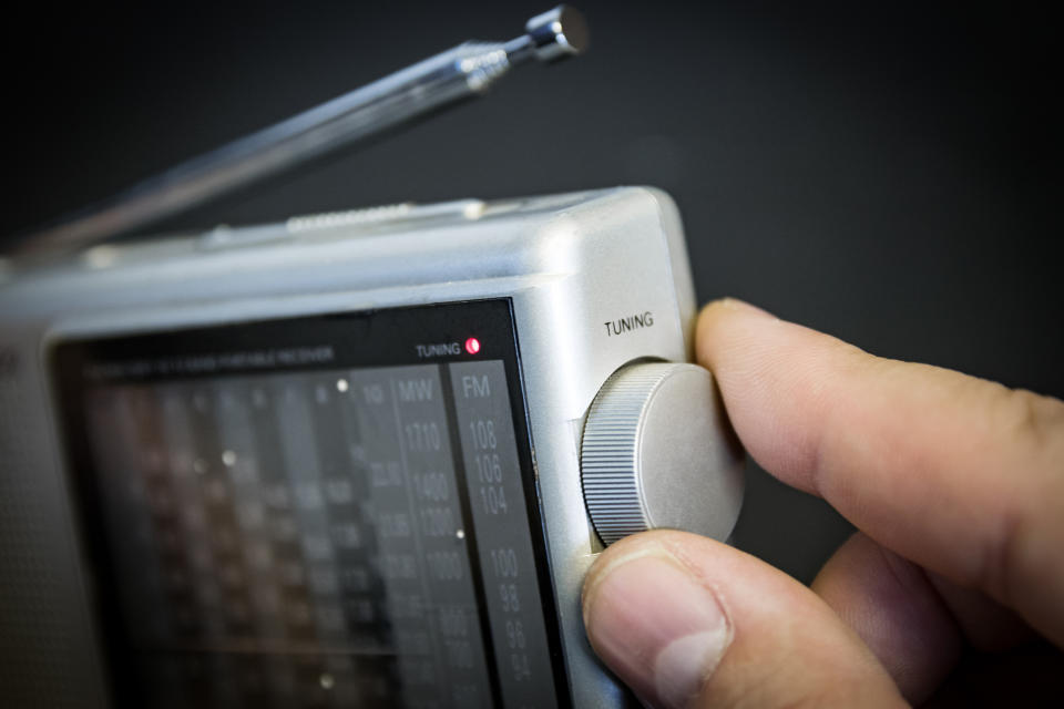 Hand tuning a portable radio with a focus on the tuning knob and frequency display