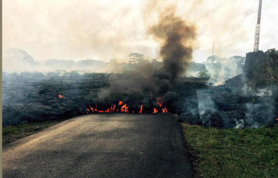 In this Oct. 24, 2014 photo from the U.S. Geological Survey, the lava flow from Kilauea Volcano that began June 27 is seen as it crossed Apa?a Street near Cemetery Road near the town of Pahoa on the Big Island of Hawaii.  Hawaii authorities on Saturday told several dozen residents near the active lava flow to prepare for a possible evacuation in the next three to five days as molten rock oozed across the country road and edged closer to homes. The USGS says the flow is currently about 160 to 230 feet (50 to 70 meters) wide and moving northeast at about 10 yards (nine meters) per hour. It's currently about six-tenths of a mile (one kilometer) from Pahoa Village Road, the town's main street. (AP Photo/U.S. Geological Survey)