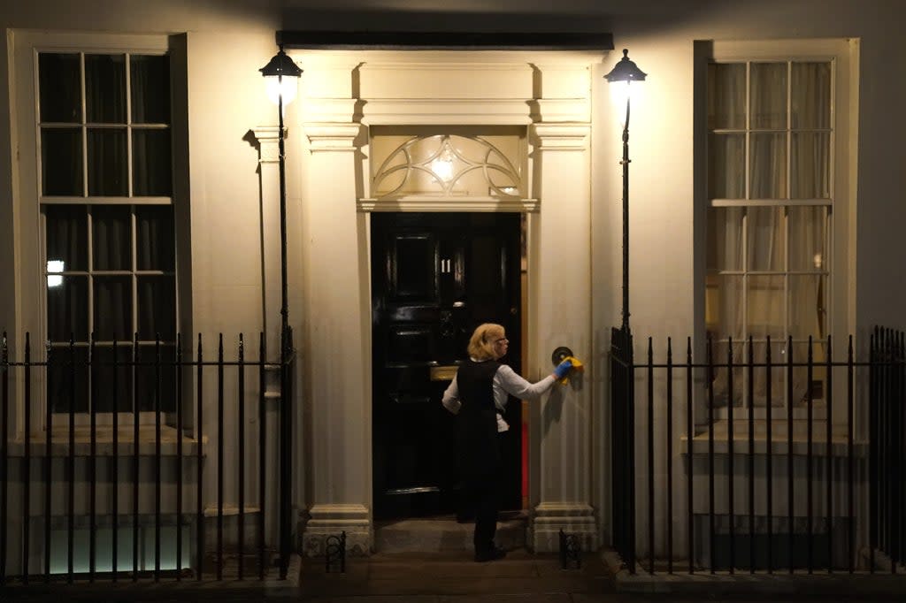 A woman polishes the door of no 11 Downing Street (PA) (PA Wire)