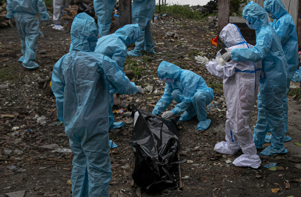 A woman, wearing white personnel protective equipment, reacts as she takes a glimpse of her husband's body, a victim of COVID-19, in Gauhati, India, Thursday, Sept. 10, 2020. India reported another record spike of 95,735 new coronavirus infections in the past 24 hours as the virus spreads beyond its major cities. The ministry said the surge in new infections is due to ramping of daily testing that exceeds 1 million now. However, experts caution that India’s outbreak is entering a more dangerous phase as the virus spreads to smaller towns and villages. (AP Photo/Anupam Nath)