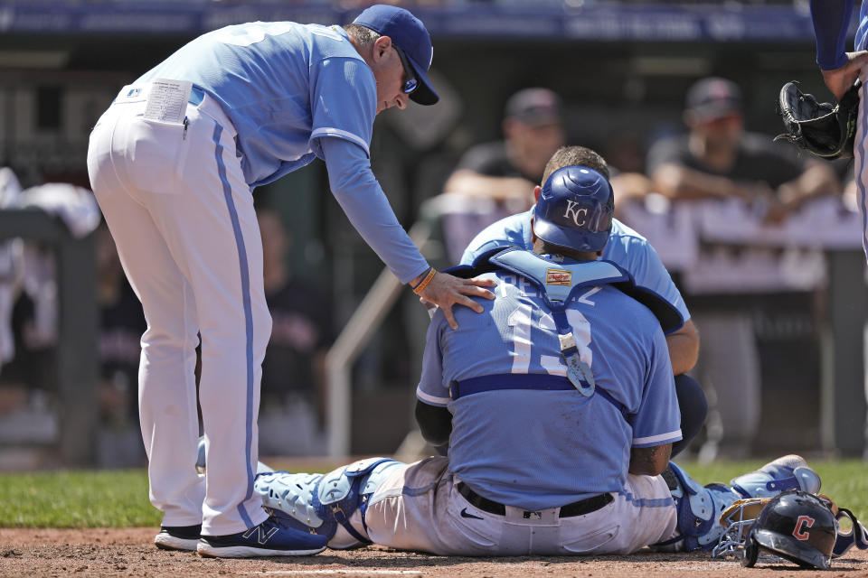 Kansas City Royals manager Matt Quatraro, left, checks on catcher Salvador Perez (13) after Perez collided with Cleveland Guardians' Jose Ramirez who stole home during the tenth inning of a baseball game Thursday, June 29, 2023, in Kansas City, Mo. The Royals won 4-3 in ten innings. (AP Photo/Charlie Riedel)