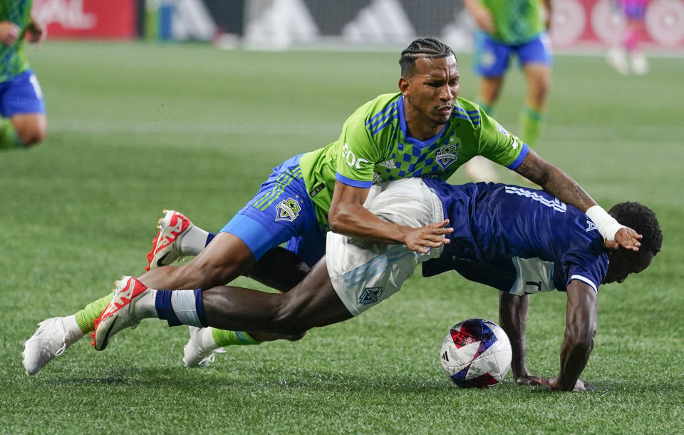 Seattle Sounders midfielder Léo Chú falls over Vancouver Whitecaps midfielder Richie Laryea during the first half of an MLS soccer match Saturday, Oct. 7, 2023, in Seattle. (AP Photo/Lindsey Wasson)