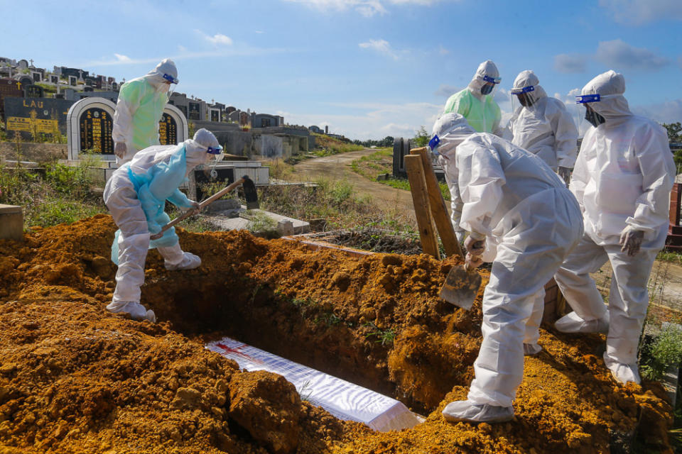 Workers wearing personal protective equipment (PPE) bury a person who died from Covid-19 at the Meru Christian Cemetery in Klang, August 9, 2021. ― Picture by Yusof Mat Isa