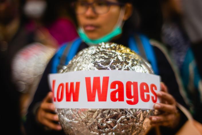 <p>An activist from the Asian Migrants Coordinating Body holds a sign that reads “Low Wages” during a protest urging the Immigration Department to review its accommodation and visa polices for foreign domestic helpers on International Women’s Day in Hong Kong on March 8, 2018. (Photo: Anthony Wallace/AFP/Getty Images) </p>