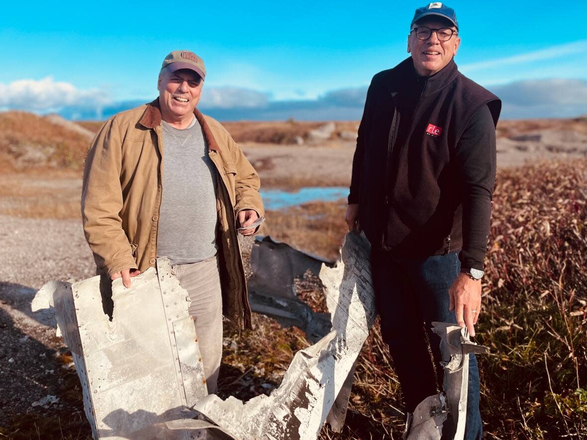 Joseph and Kevin Galie hold up a piece of B-24 bomber the Bad Penny. (Leila Beaudoin - image credit)