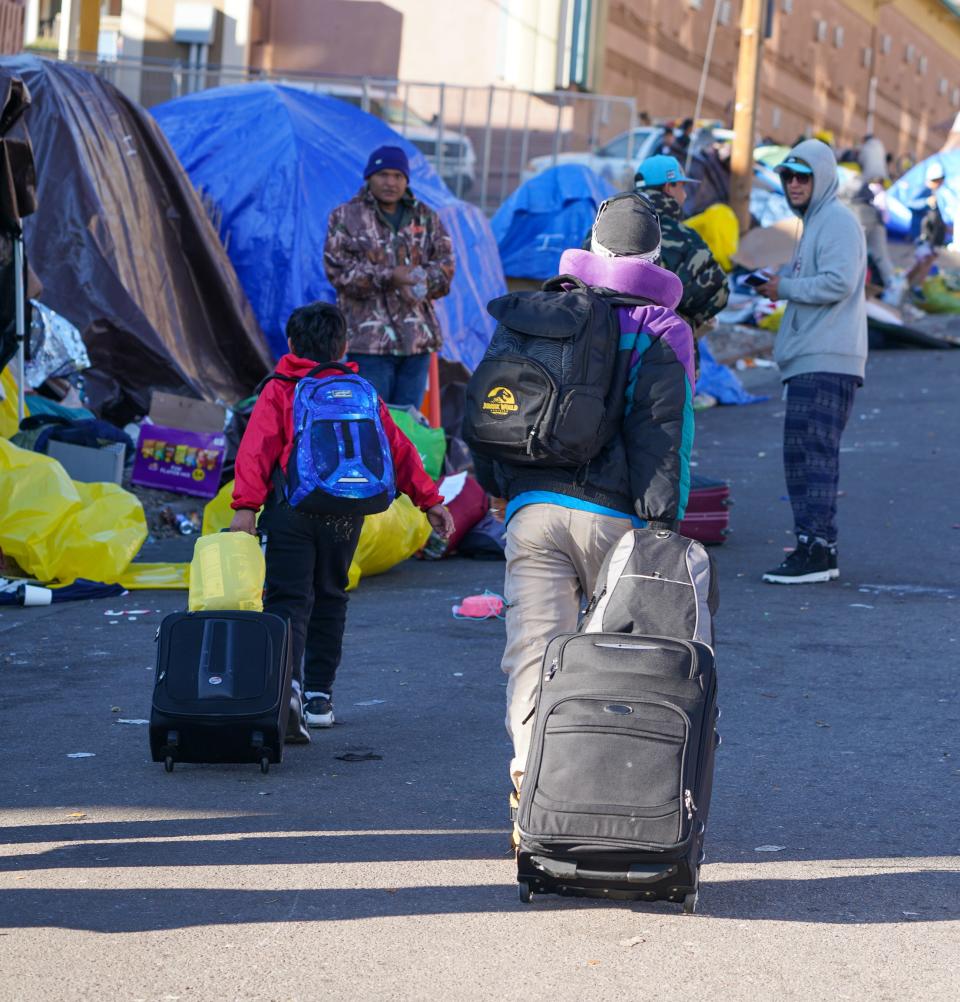 Migrants carrying their belongings walk though an illegal tent encampment as city officials close it down and evict everyone on Jan, 3, 2024.