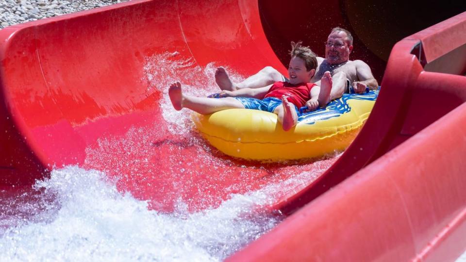 People ride a water slide on a hot June day.