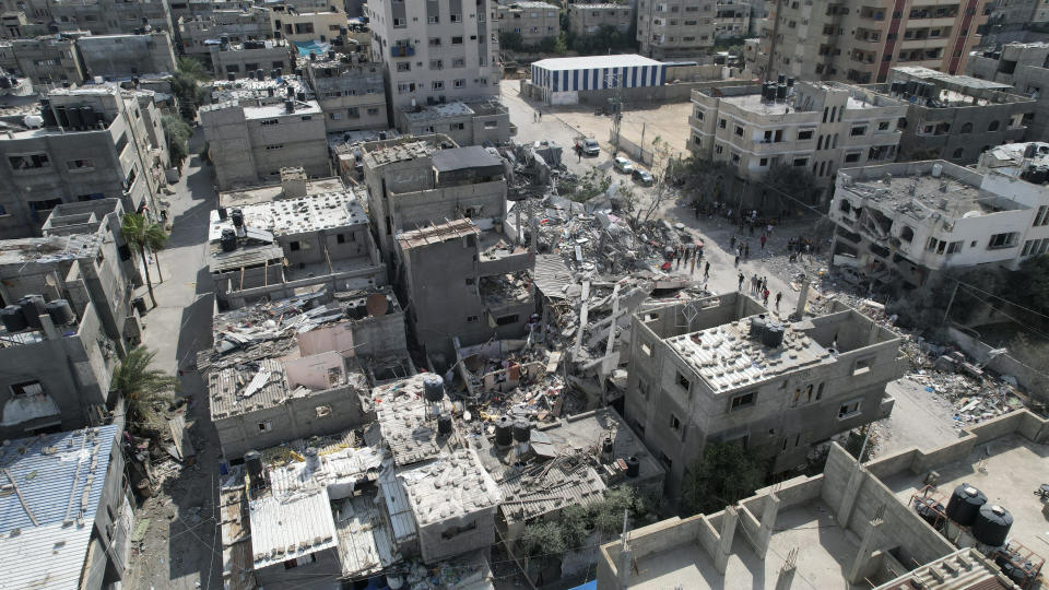 Palestinians stand by the building destroyed in an Israeli airstrike in Nuseirat camp in the central Gaza Strip, Monday, Oct. 16, 2023. (AP Photo/Hatem Moussa)