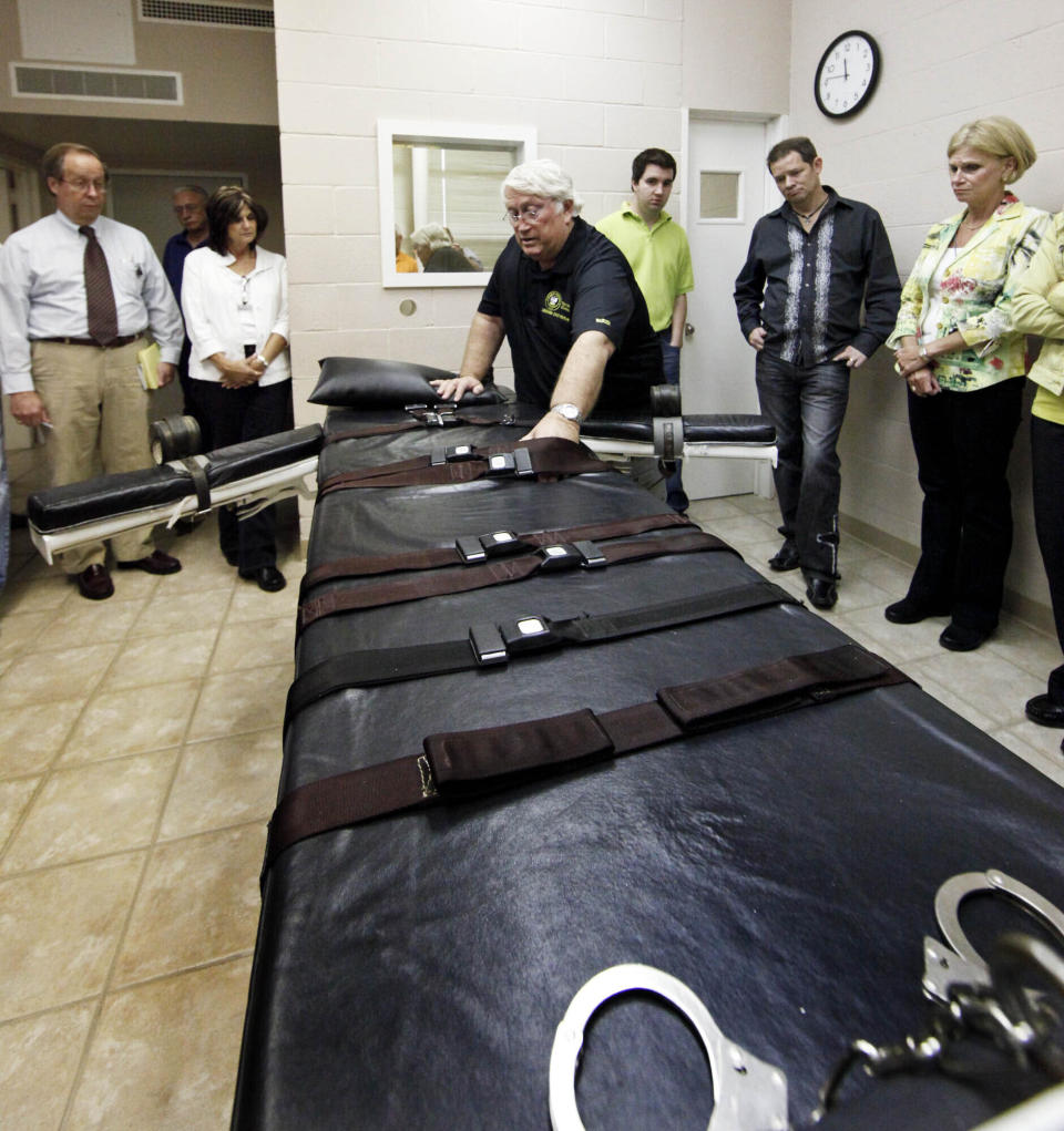 FILE - In this Sept. 18, 2009, file photo, Warden of the Louisiana State Penitentiary, Burl Cain, discusses the gurney used for lethal injections to Ruth Graham, far right and others as they visit the Louisiana State Penitentiary in Angola, La. Louisiana cleans its execution chamber at the state penitentiary daily, but it's been more than a decade since a condemned prisoner has laid on the chamber's black-padded gurney to die. Sixty-eight people sit on Louisiana’s death row, with no execution dates set. Though the state historically has been tough on crime and holds the dubious distinction as the nation's incarceration capital, Louisiana seems to be doing very little to carry out its death penalty. (AP Photo/Judi Bottoni, File)