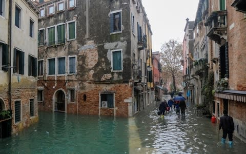 People walking outside during exceptionally high water levels in Venice - Credit: Reuters
