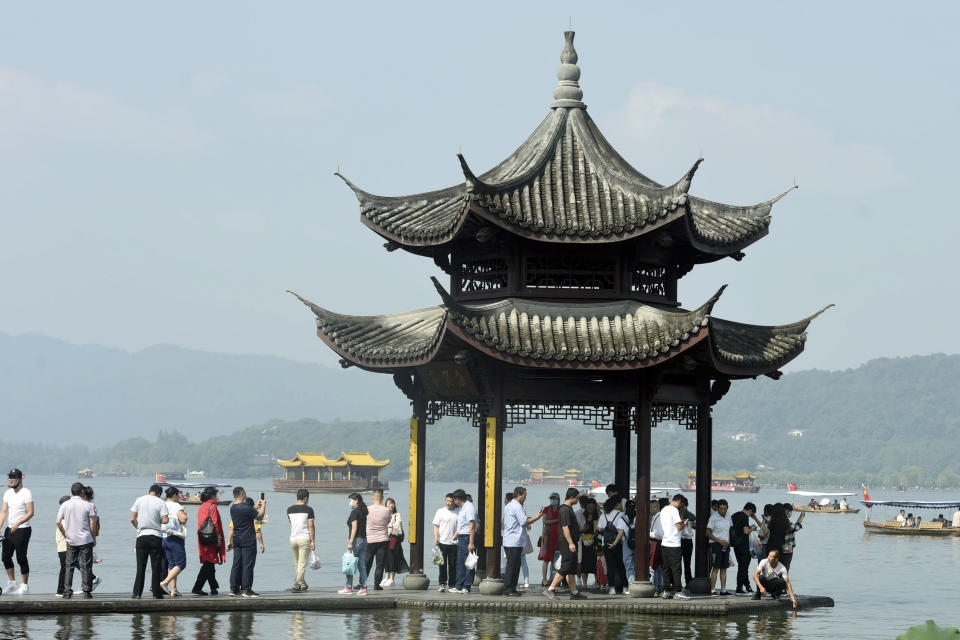 Tourists gather at a waterfront pavilion at the West Lake in Hangzhou in eastern China's Zhejiang Province, Thursday, Oct. 1, 2020. Millions of Chinese tourists usually would use their week-long National Day holidays to travel abroad. This year, travel restrictions due to the coronavirus pandemic mean that some 600 million tourists - about 40% of the population - will travel within China during the holiday that began Thursday, according to Ctrip, China's largest online travel agency. (Chinatopix via AP)