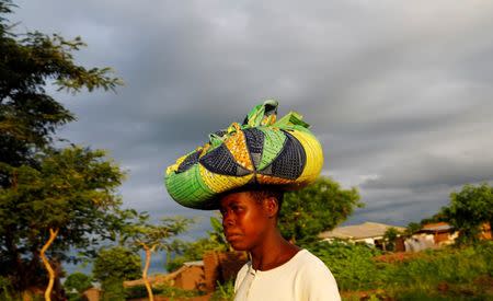 Rain clouds loom as Malawian subsistence farmer Louise Abele carries maize she has bought to feed her family near the capital Lilongwe, Malawi January 31, 2016. REUTERS/Mike Hutchings