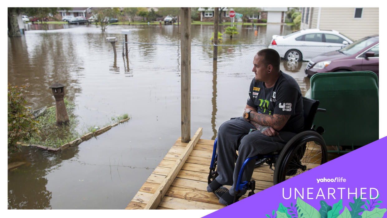 A man in a wheelchair at his home while surrounded by floodwaters.