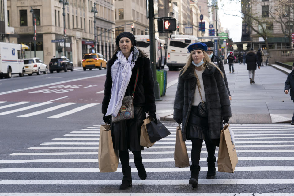 FILE - Women carry shopping bags, Thursday, Dec. 10, 2020, in New York. Shoppers, who can't touch or feel products they're ordering, are expected to return items during the holiday season at a rate double from last year, costing retailers roughly $1.1 billion, according to Narvar Inc., a software and technology company that manages online returns for hundreds of brands. That puts retailers in a conundrum: they don't want the returns, but they also want to make shoppers feel comfortable to freely buy without worry. (AP Photo/Mark Lennihan)