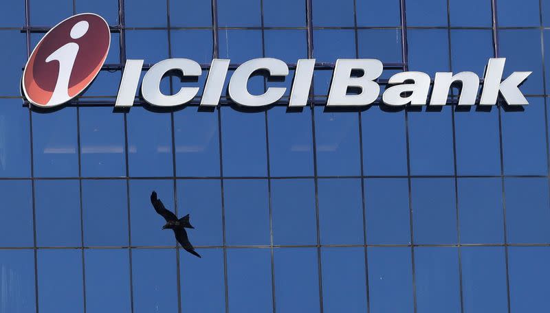 A bird flies past the facade of the ICICI bank head office in Mumbai