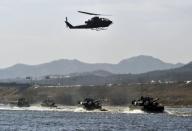 South Korean K1A1 tanks cross a river as an AH-1S helicopter flies overhead during a military drill in Wonju, east of Seoul, on February 8, 2012. Over the past five years, Asia and Oceania accounted for 44 percent in volume of conventional arms imports, the Stockholm International Peace Research Institute said
