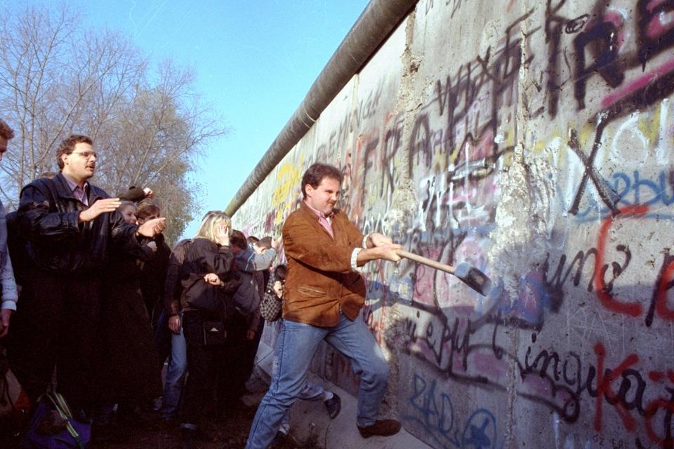 An unidentified West Berliner swings a sledgehammer, trying to destroy the Berlin Wall near Potsdamer Platz, on November 12, 1989, where a new passage was opened nearby. 