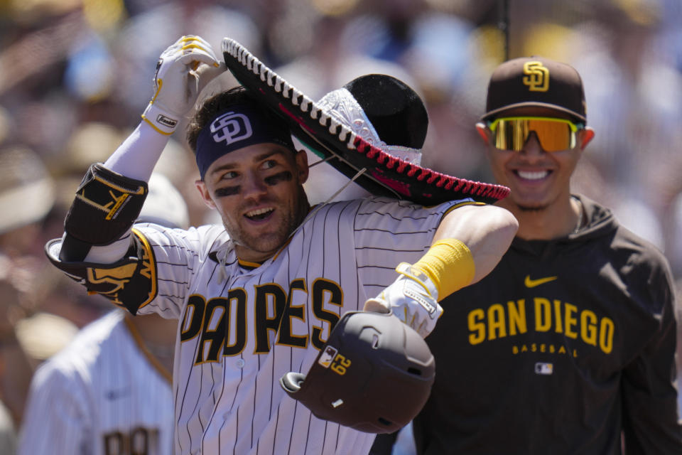 FILE - San Diego Padres' Brett Sullivan, left struggles with a sombrero after hitting a two-run home run as teammate Manny Machado looks on, right, against the Cincinnati Reds, Wednesday, May 3, 2023, in San Diego. About half the clubs in MLB are using some kind of prop or ritual to celebrate a big hit or a big play in ways that often go viral. (AP Photo/Gregory Bull)