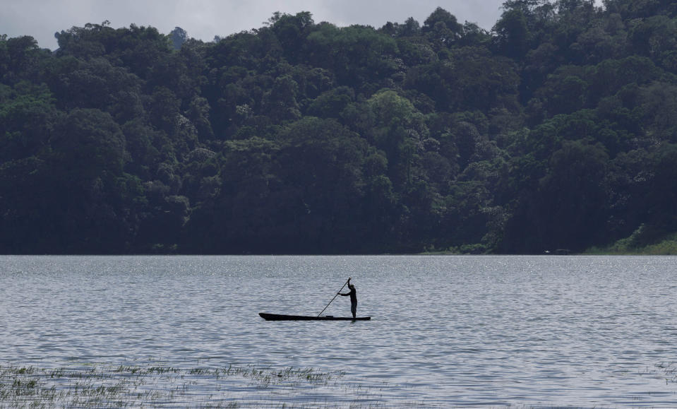 A fisherman rows his boat on the Tamblingan lake in Buleleng, Bali, Indonesia, Saturday, April 16, 2022. In less than a decade, Bali's water table has decreased over 50 meters (164 feet) in some areas, raising concerns that it could lead to worsening water crisis on the tropical tourist destination. (AP Photo/Tatan Syuflana)