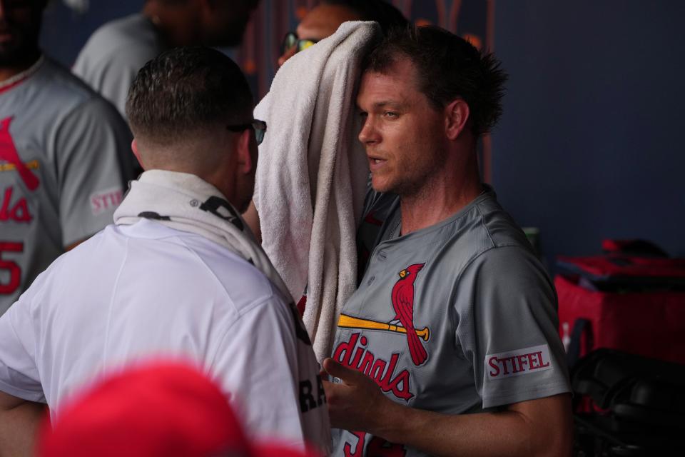 Cardinals pitcher Sonny Gray talks with a trainer in the dugout during spring training.