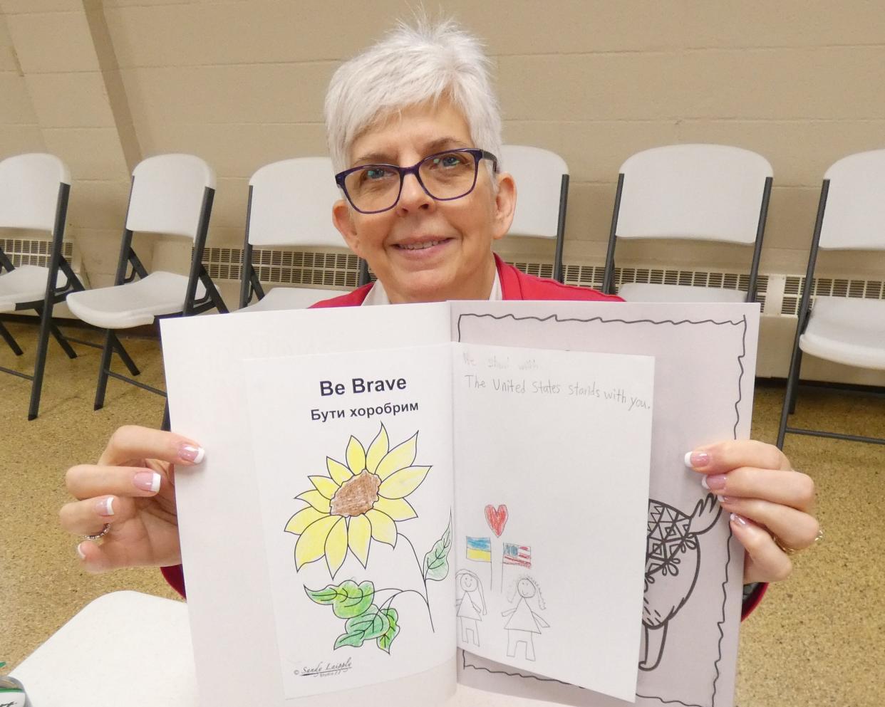 Debbra Grace displays one child's message for Ukrainian refugee children.