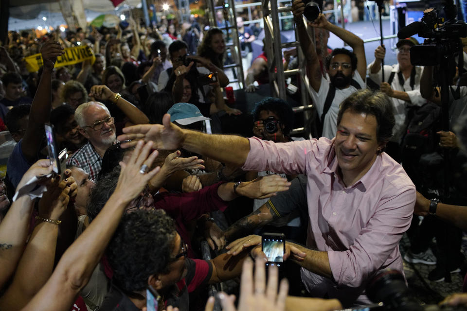 Fernando Haddad, who ran in the last presidential race backed by the Workers' Party, right, greets supporters during a protest against cuts in Brazil's public education sector at Cinelandia square, Rio de Janeiro, Brazil, Friday, May 10, 2019. Students and teachers gathered in the city's center Friday, taking a stand against the administration of fair-right President Jair Bolsonaro. (AP Photo/Ricardo Borges)