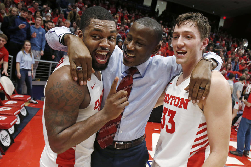 FILE - In this Feb. Feb. 28, 2020, file photo, Dayton coach Anthony Grant, center, gives a hug to players Trey Landers, left, and Ryan Mikesell following the team's 82-67 win over Davidson in an NCAA college basketball game in Dayton, Ohio. The coronavirus outbreak has abruptly roused the University of Dayton from its dream of a basketball season. The 29-2 Flyers were rolling into tournament play on a 20-game winning streak that had lifted spirits in an Ohio city battered in the past year by violent deaths and devastation. The NCAA decision to cancel March Madness ended hopes for the small Roman Catholic school’s first Final Four appearance in 53 years. (AP Photo/Gary Landers, File)