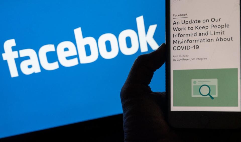 Smart phone screen displays a new policy on Covid-19 misinformation with a Facebook website in the background (AFP via Getty Images)