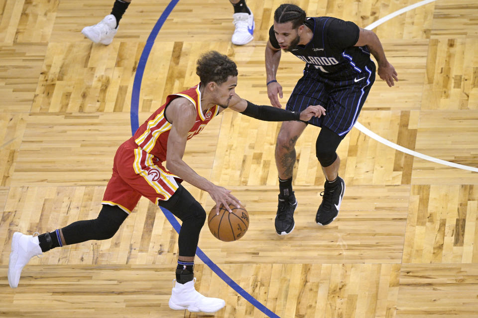 Atlanta Hawks guard Trae Young, left, drives to the basket in front of Orlando Magic guard Michael Carter-Williams (7) during the first half of an NBA basketball game Wednesday, March 3, 2021, in Orlando, Fla. (AP Photo/Phelan M. Ebenhack)