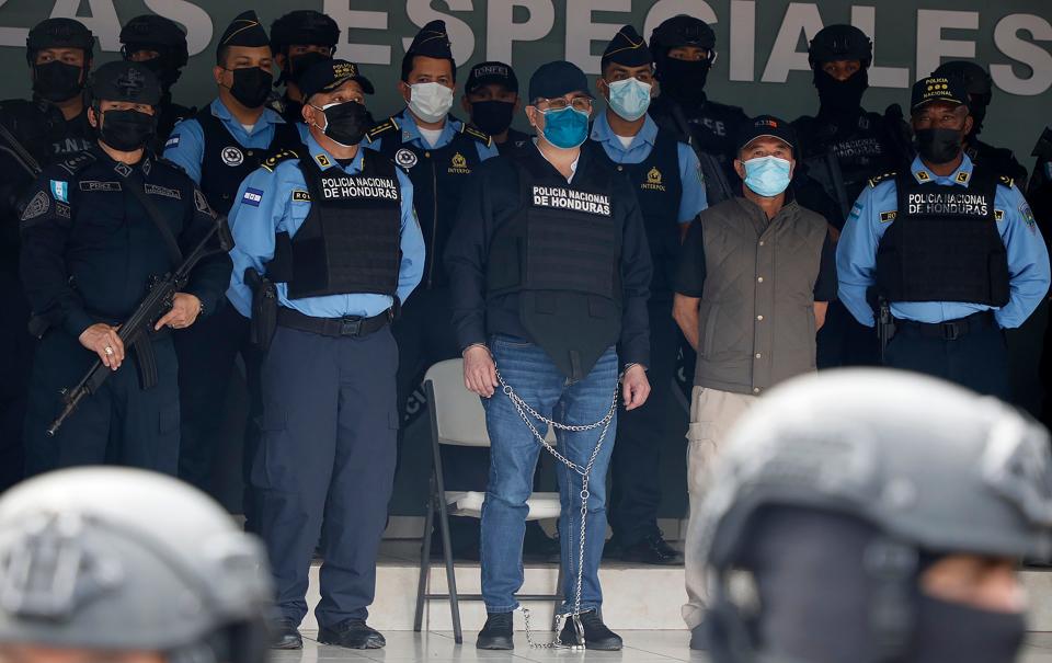 Former Honduran President Juan Orlando Hernández, center in chains, is shown to the press at the Police Headquarters in Tegucigalpa, Honduras, Tuesday, Feb. 15, 2022.