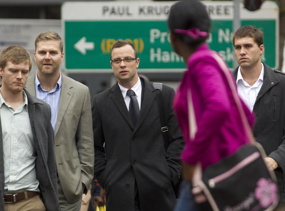 Oscar Pistorius, center, accompanied by unidentified men arrives at the high court for his trial in Pretoria, South Africa, Tuesday, March 11, 2014. Pistorius is charged with murder for the shooting death of his girlfriend, Reeva Steenkamp, on Valentines Day in 2013. (AP Photo/Themba Hadebe)