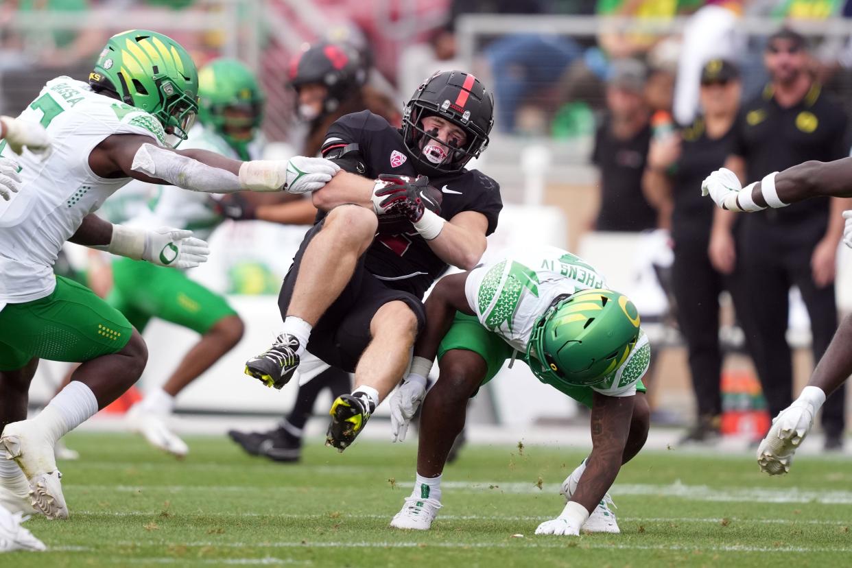 Stanford running back Casey Filkins, center, is tackled by Oregon Ducks defensive back Steve Stephens IV, right, and linebacker Jeffrey Bassa, left, during the second quarter at Stanford Stadium Saturday, Sept. 30, 2023.