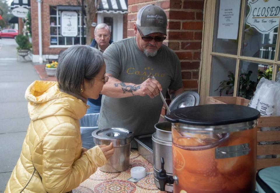 Robert Chanonat serves free hot soup to Okyoun Janicki Wednesday Dec. 7, 2022 outside Sweet Basil Cafe in Southern Pines shortly after power was restored. Two deliberate attacks on electrical substations in Moore County Saturday evening caused days-long power outages for tens of thousands of customers.