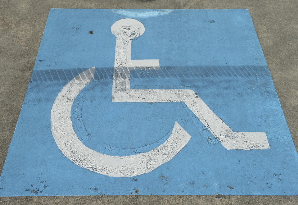 A close up of the blue wheelchair sign painted on a car park. 