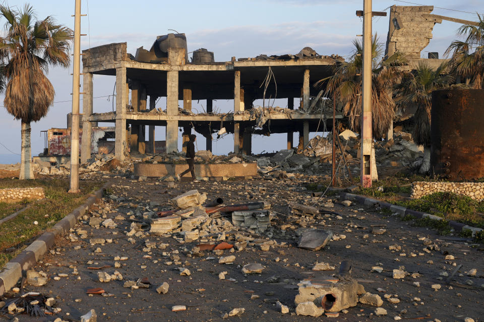 A young man walks through the rubble of a destroyed building hit by Israeli airstrikes in Gaza City, Monday, Feb. 13, 2023. Earlier on Monday, the Israeli military said aircraft bombed a Hamas rocket manufacturing site and military installations in the Gaza Strip after Palestinian militants launched four rockets into southern Israel overnight. (AP Photo/Adel Hana)