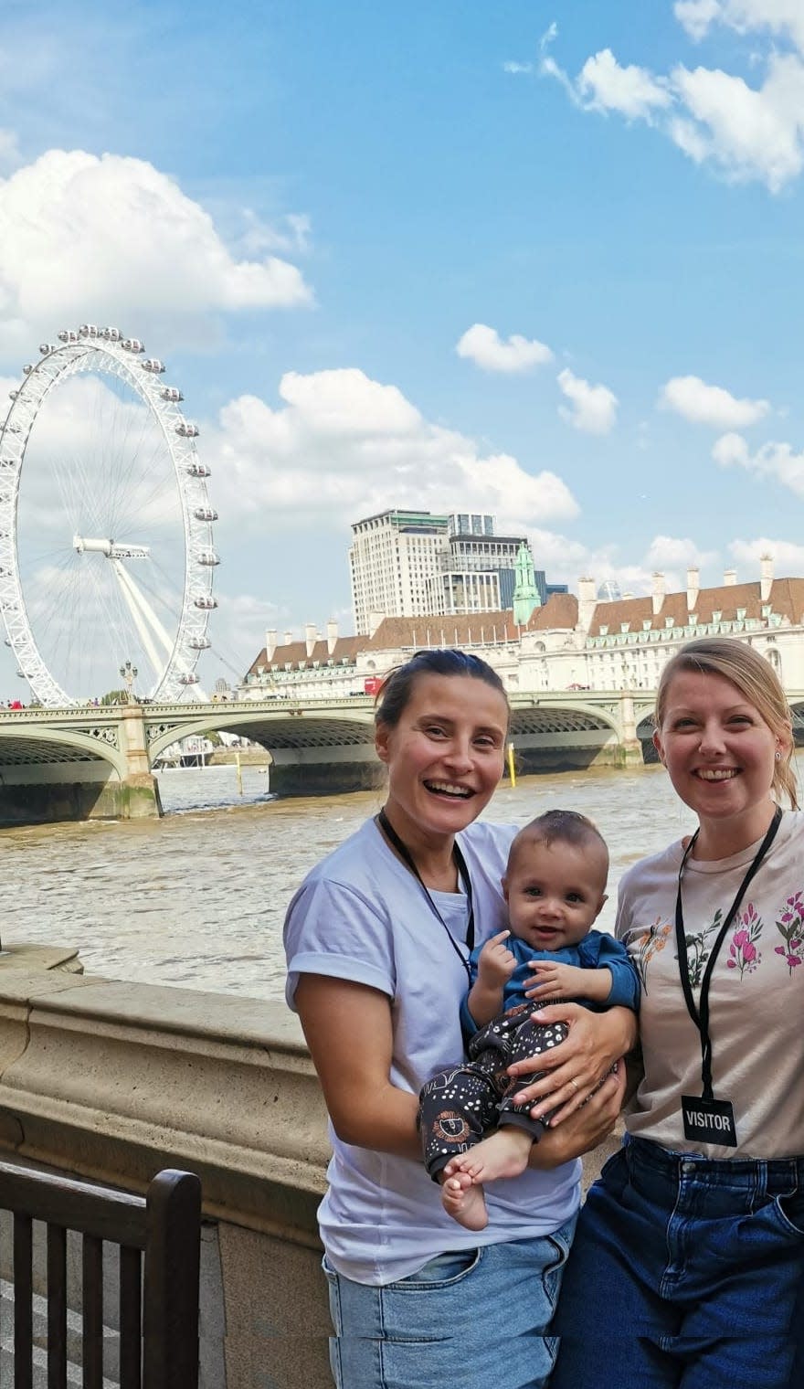 Anna (right), her wife (left), and their son (middle) in front of a ferris wheel on a pier