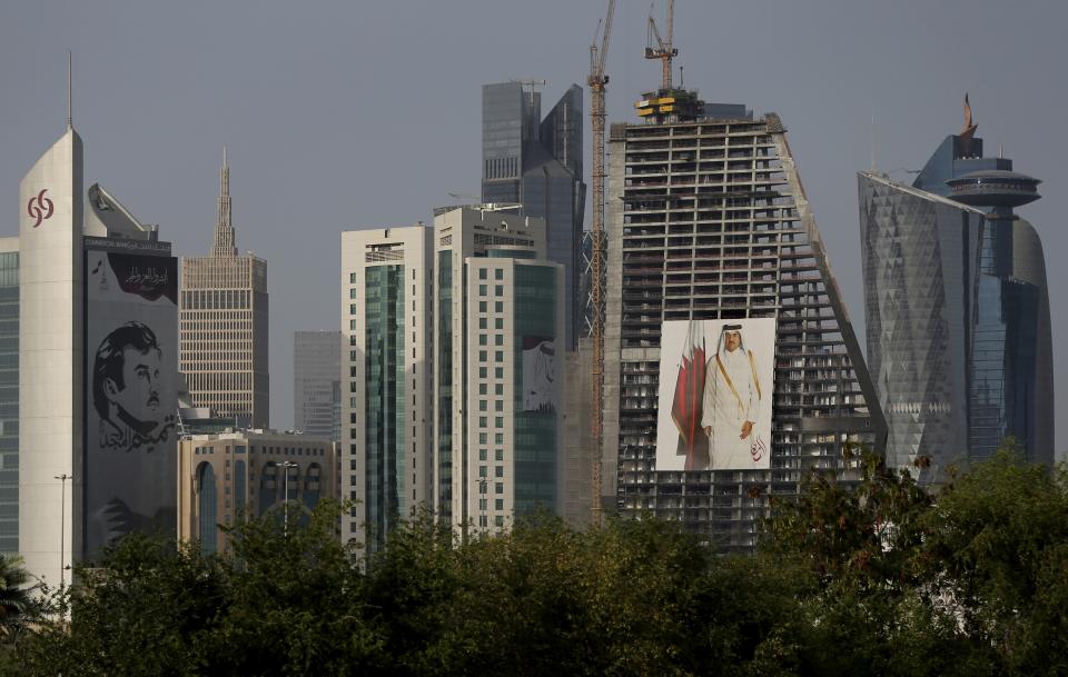 FILE - In this May 5, 2018, file photo, the images of the Emir of Qatar, Sheikh Tamim bin Hamad Al Thani hang on the towers in Doha, Qatar. Qataris awoke to a surprise blockade and boycott by Gulf Arab neighbors 3 1/2 years ago, and this week were jolted again by the sudden announcement that it was all over. (AP Photo/Kamran Jebreili, File)