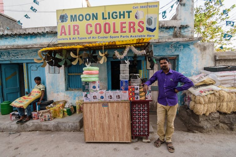 Man stands in front of Air Coolers shop sign