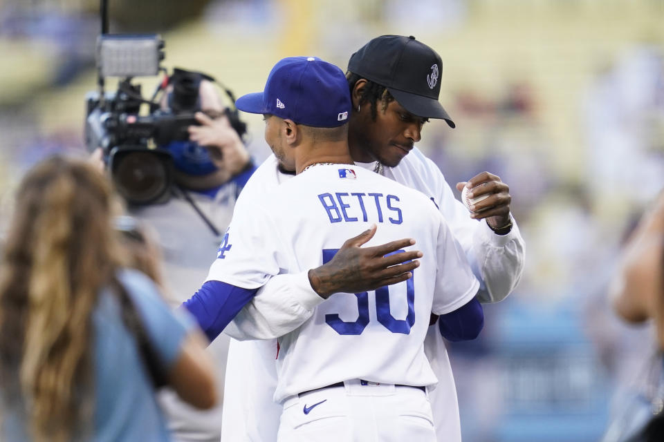 Los Angeles Rams cornerback Jalen Ramsey hugs Los Angeles Dodgers right fielder Mookie Betts (50) after throwing out the first pitch at a baseball game between the Milwaukee Brewers and the Los Angeles Dodgers Saturday, Oct. 2, 2021, in Los Angeles. (AP Photo/Ashley Landis)