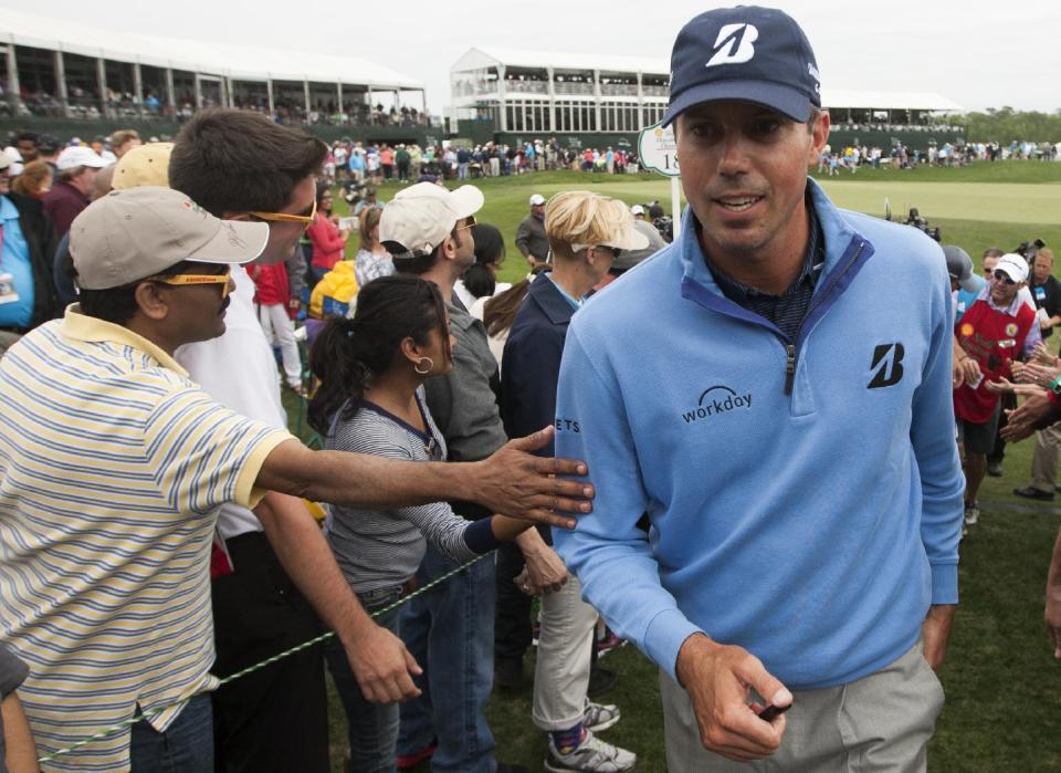 Matt Kuchar, right, is greeted by fans as he walks off the eighteenth green during the third round of the Houston Open golf tournament on Saturday, April 5, 2014, in Humble, Texas. (AP Photo/Patric Schneider)