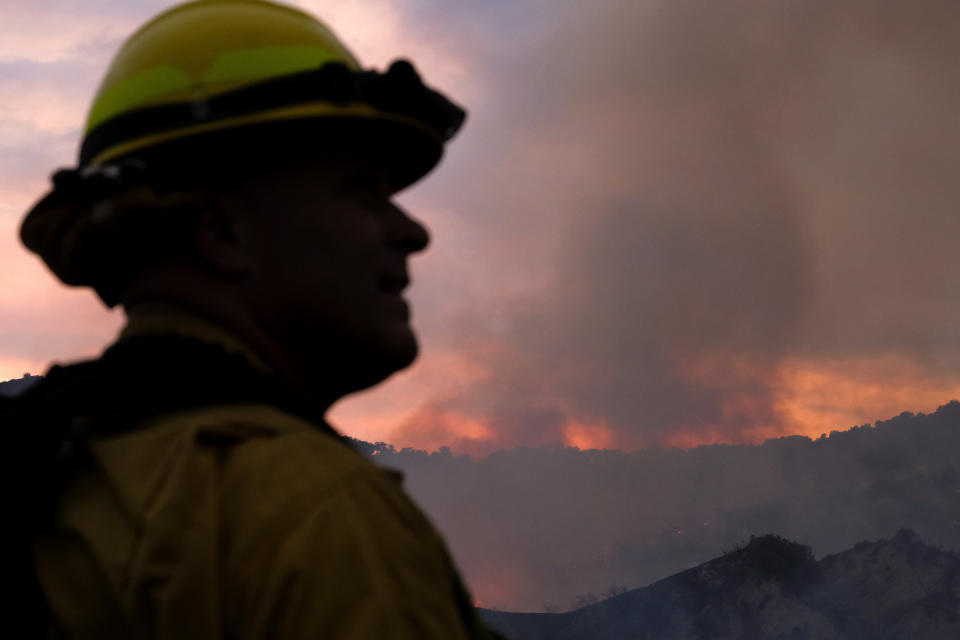 A firefighter keeps watch as smoke rises from a brush fire scorching at least 100 acres in the Pacific Palisades area of Los Angeles on Saturday, May 15, 2021. (AP Photo/Ringo H.W. Chiu)