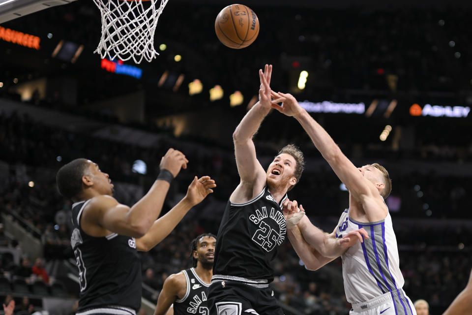 Sacramento Kings' Domantas Sabonis, right, fights for possession with San Antonio Spurs' Jakob Poeltl (25) and Keldon Johnson during the first half of an NBA basketball game, Wednesday, Feb. 1, 2023, in San Antonio. (AP Photo/Darren Abate)