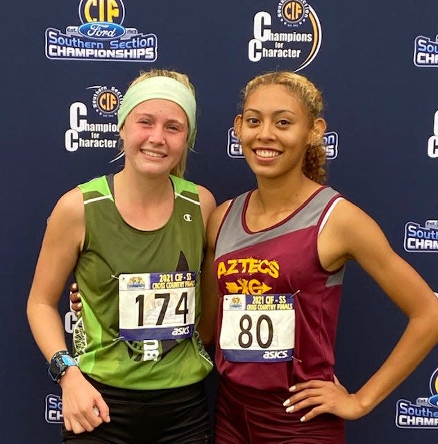 Barstow’s Angelina Vasquez, right, and Burroughs' Leah Tomlinson pose for a photo after competing in the girls Division 4 race at the CIF-Southern Section Cross Country Finals on Nov. 20, 2021.