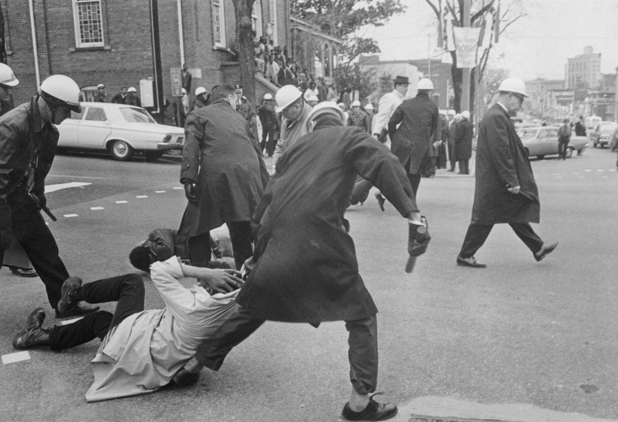 Police with batons drag away African American protesters who had lain down in a city street in an act of passive resistance.