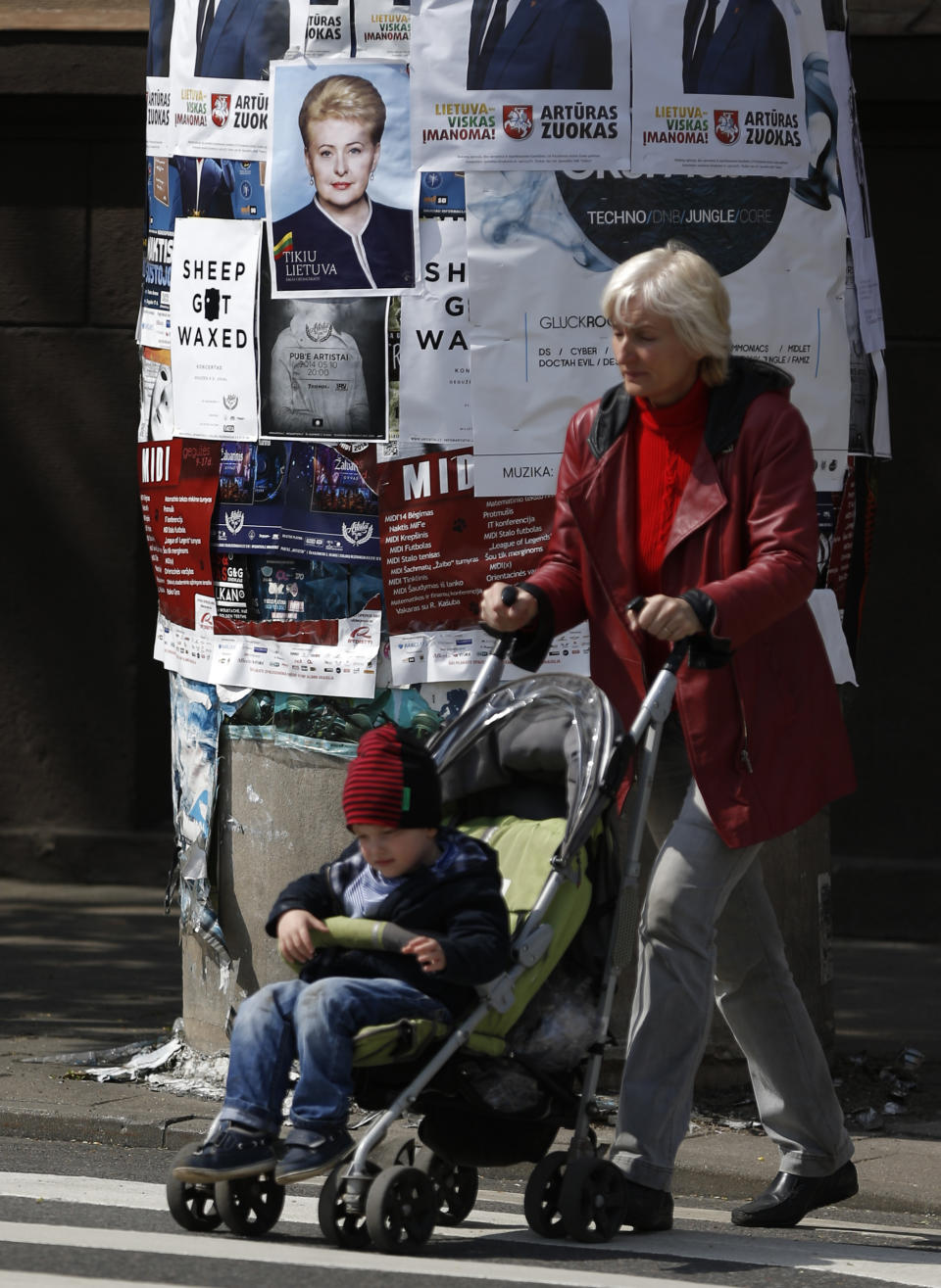 A local resident walks by an election poster showing Lithuania's President Dalia Grybauskaite, a presidential candidate, in Vilnius, Lithuania, Friday, May 9, 2014. The poster reads " I believe in Lithuania" . Lithuanians will ballot Sunday, May 11, in a first round of presidential elections. (AP Photo/Mindaugas Kulbis)